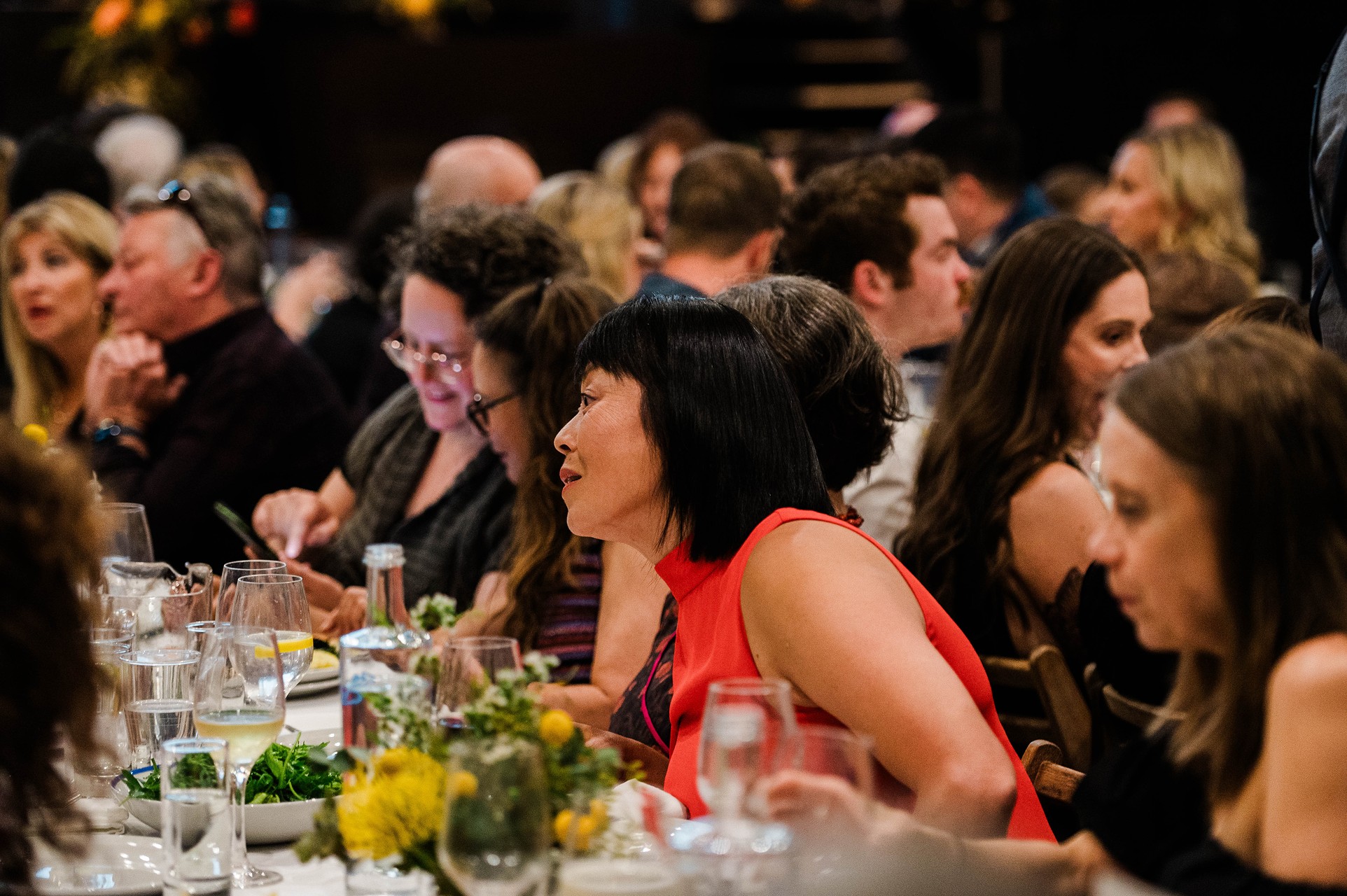 A woman talks to another person over a dinner table