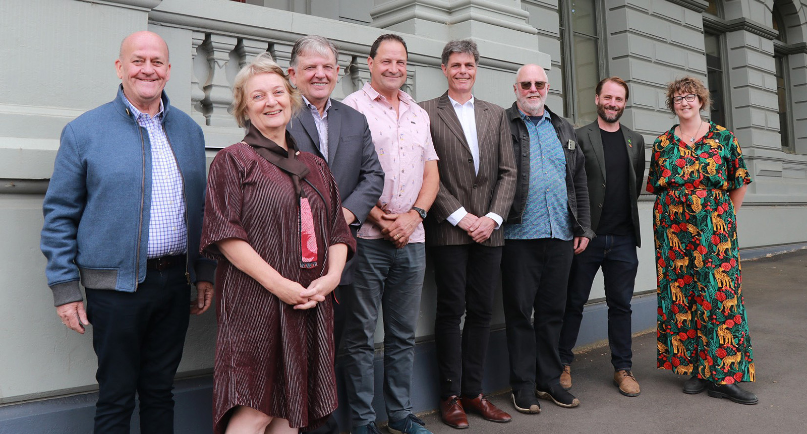 Eight people standing in a line smiling.