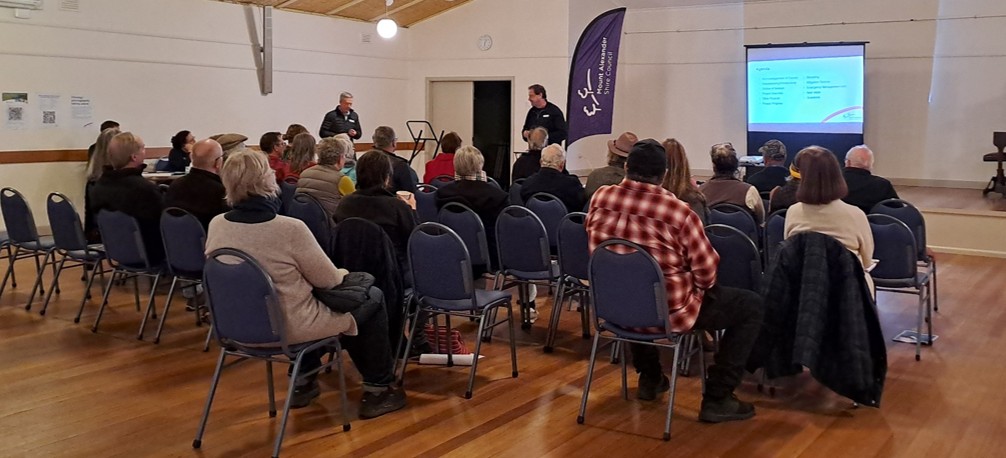 An image taken from behind a group of people watching a presentation inside Newstead community Centre.