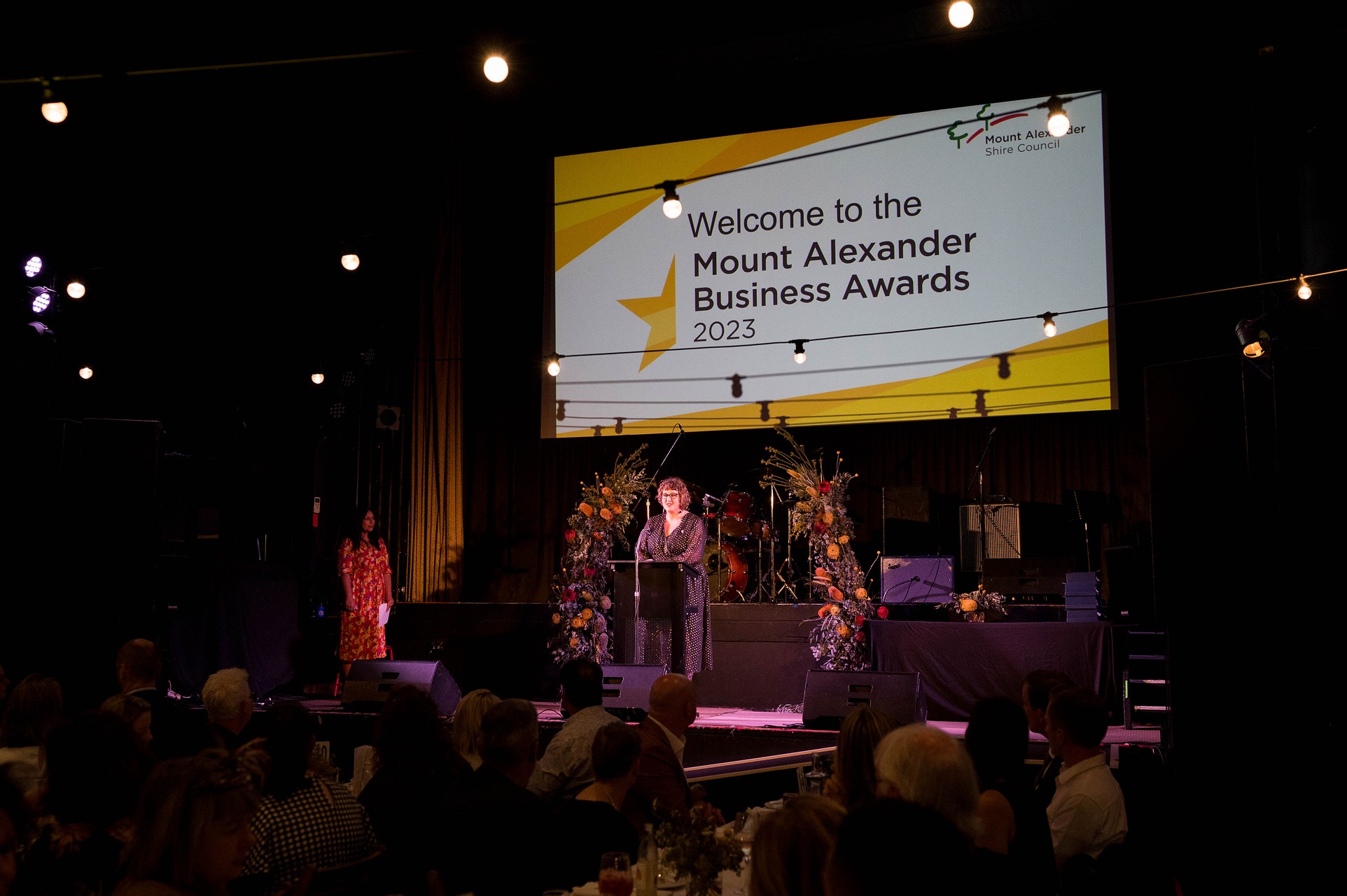 A woman presents an award on a stage